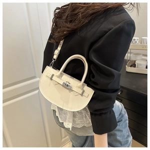Vue latérale du sac Kelly en cuir blanc avec boucle en métal et bandoulière réglable