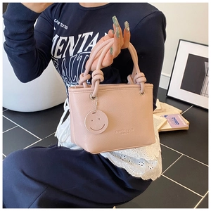Detailed view of pink textured leather bucket bag with fashion logo and knot handle strap