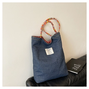 Détail du sac cabas en denim avec anses tressées colorées et doublure à carreaux
