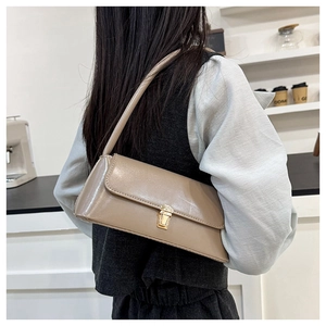Close-up of minimalist khaki baguette bag featuring a polished gold-tone metal buckle