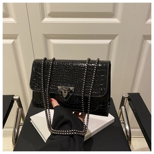 Close-up of black crocodile texture faux leather bag with vintage metal lock and chain