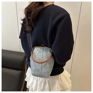 Detail of light blue denim purse with crystals, retro silver clasp, and round top handle
