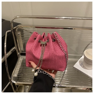 Détail du sac seau rose tissé avec cordon à perles élégant et fine chaîne argentée