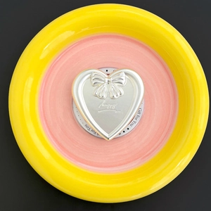 Close-up of silver heart-shaped phone grip with bow relief and happy engraving