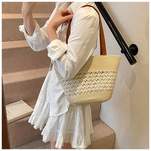 Detail of hollow-out straw tote bag with brown leather handles for summer beach style