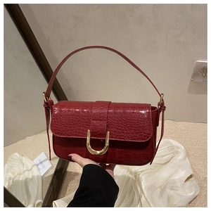 Detail of dark red crocodile pattern leather bag with large golden U-shaped buckle