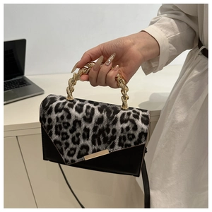 Detail of leopard print crossbody bag with gold woven handle and envelope flap design