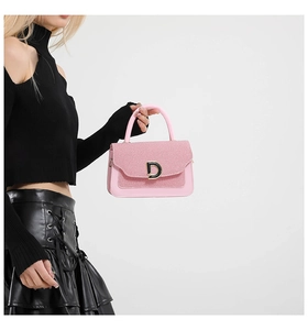 Dettaglio della borsa in pelle rosa con patta intrecciata e fibbia in metallo dorato a D