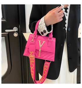 Detail of rose red crossbody bag featuring gold V-logo and jacquard wide strap