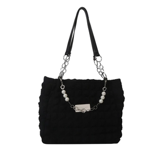Black bubble quilted tote bag with chain strap and pearl accents on white background