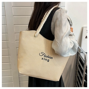 Detail of macaron beige tote bag featuring woven texture and rope shoulder handles