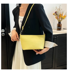Détail macro du sac seau jaune vif en cuir grainé litchi avec logo embossé chic