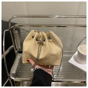 Détail du sac seau en paille beige avec cordon chaîne argentée et perle décorative