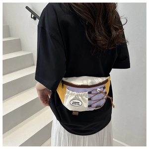 Détail d'un sac banane en toile multicolore avec sangle ajustable porté par un modèle