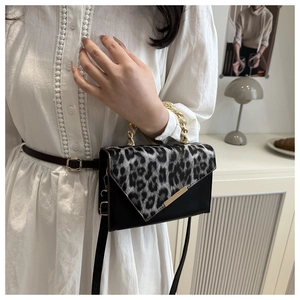 Detail of leopard print crossbody bag featuring gold chain handle and black PU leather body