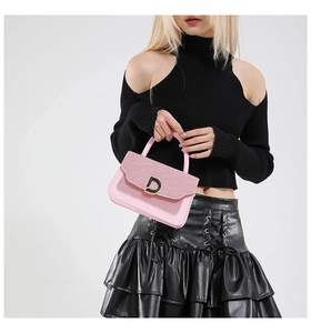 Dettaglio della borsa rosa con patta di paillettes e fibbia a D dorata indossata da modella