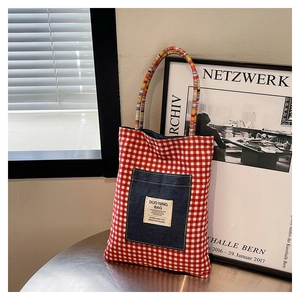 Détail du sac cabas en toile à carreaux rouges et blancs avec poche denim et anses en corde