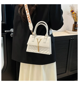 Detailed side view of white crossbody bag featuring gold V logo and patterned wide strap