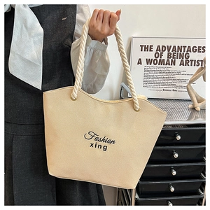 Close-up of beige canvas tote bag featuring thick rope handles and fashion print