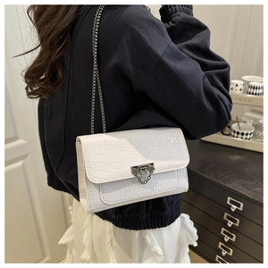 Detail of white crocodile embossed shoulder bag with dark metal chain strap for women