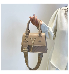 Close-up of tan quilted square handbag featuring a gold V-logo and patterned strap