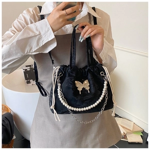 Detailed shot of black velvet drawstring bag with golden butterfly and pearl chain