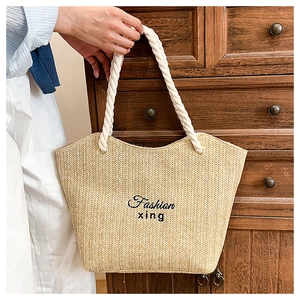 Detail of hand-woven straw tote bag with cotton rope handles and Fashion xing logo