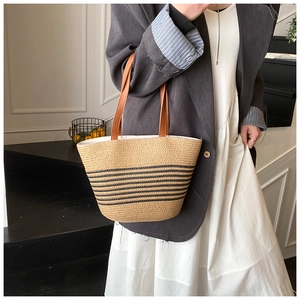Detail shot of handwoven straw tote with black stripes and brown leather straps