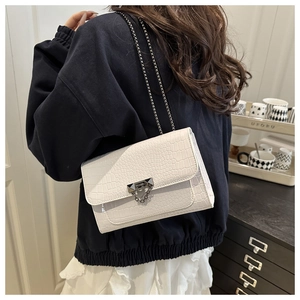 Detail of white crocodile texture crossbody bag with silver chain and metal lock