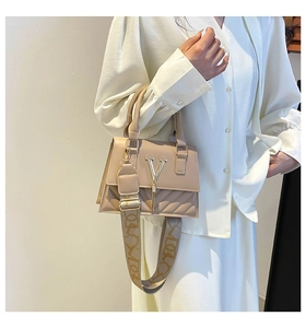 Detail of beige quilted crossbody bag with metal V logo and patterned wide strap
