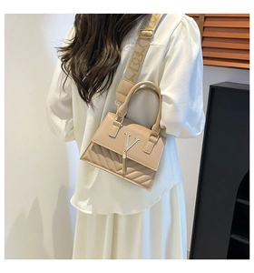 Detail of beige shoulder bag with metal V-logo, tassel charm and quilted wave pattern