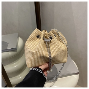 Détail du sac seau en paille avec cordon perlé et bandoulière chaîne argentée