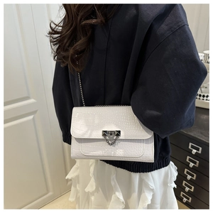 Close-up of white crocodile pattern shoulder bag with silver metal chain and buckle