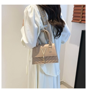 Detail of milk tea quilted bag with V-shaped gold logo and geometric fabric strap