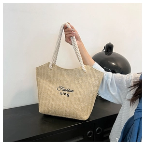 Detail of hand-woven straw tote bag with cotton rope handles and fashion embroidery