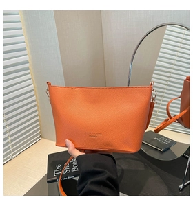 Détail d'un sac seau en cuir grainé orange vif avec ferrures argentées et logo gravé