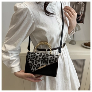 Detail of leopard print flap and golden twisted metal handle on a black leather bag