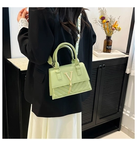 Detail of mint green PU bag featuring V-shaped gold buckle and stylish tassel fringe