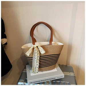 Detail of straw woven tote with black stripes and a large white lace ribbon bow