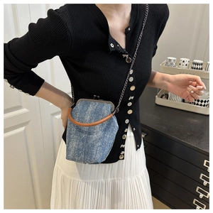 Detailed view of vintage denim kiss-lock bag with brown handle and silver chain strap