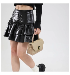 Dettaglio mini gonna in pelle PU a balze con lacci decorativi incrociati sulla parte frontale