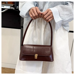 Detail of a vintage dark brown leather baguette bag featuring a sleek gold metal buckle clasp