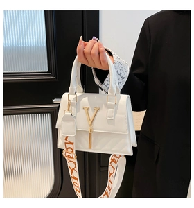Close-up of white leather handbag with golden V logo, tassels and printed strap