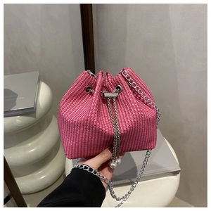 Détail du sac seau tissé rose avec fermeture à cordon, perles et bandoulière chaîne