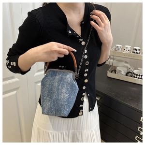 Detail of vintage denim clip bag with silver glitter and brown leather handle on a model