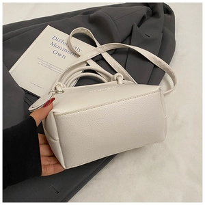 Detail view of white lychee texture leather bucket bag with top handles and strap