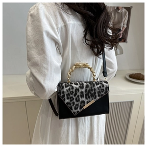 Fashionable leopard print handbag with golden metallic handle shown on model's shoulder