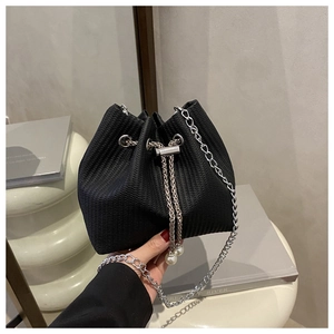 Détail du sac seau noir texturé avec cordon perlé et fine bandoulière en chaîne argentée