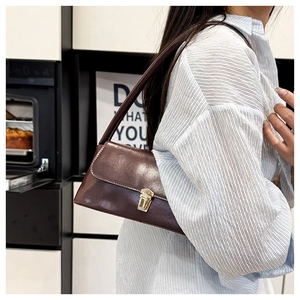 Detail of dark brown baguette bag with golden buckle worn with a striped shirt