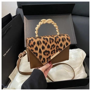 Detail showing leopard print texture and gold woven handle of the shoulder bag